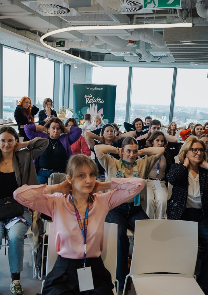 pracownicy podczas aktywnej przerwy na evencie firmowym - ćwiczenia w sali bez zmiany stroju 